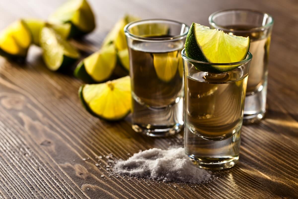 Tequila u čašama na stolu, uz limun i so - priprema za savršen užitak.